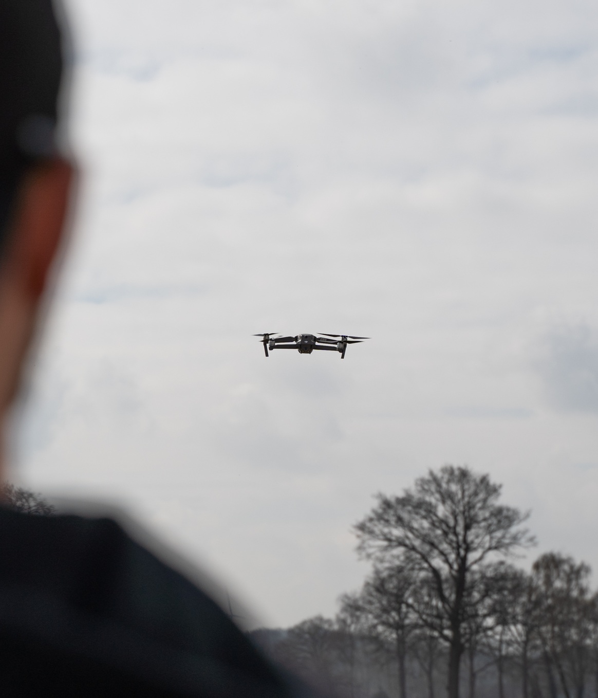 Foto einer fliegenden Drohne, vorne im Anschnitt der Kopf eines Betrachters