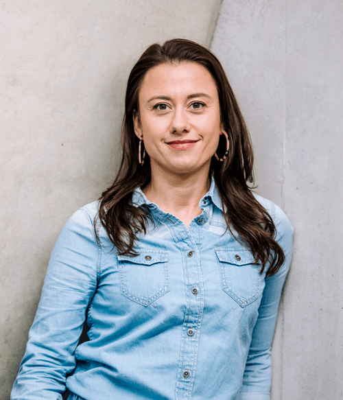 Selbstbewusste Frau mit offenem Blick und legerem Jeanshemd vor Betonwand – steht für moderne, teilnehmendenorientierte VdS-Fortbildungen mit starkem Praxisbezug und individueller Unterstützung.