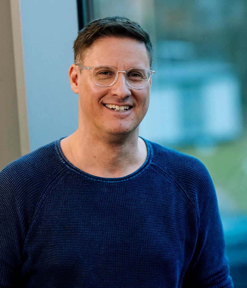 Sympathischer Mann mit entspanntem Lächeln vor moderner Glasfassade – steht für praxisnahe, qualitativ hochwertige VdS-Fortbildungen mit erstklassigen Referenten.