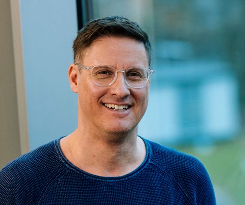 Sympathischer Mann mit entspanntem Lächeln vor moderner Glasfassade – steht für praxisnahe, qualitativ hochwertige VdS-Fortbildungen mit erstklassigen Referenten.